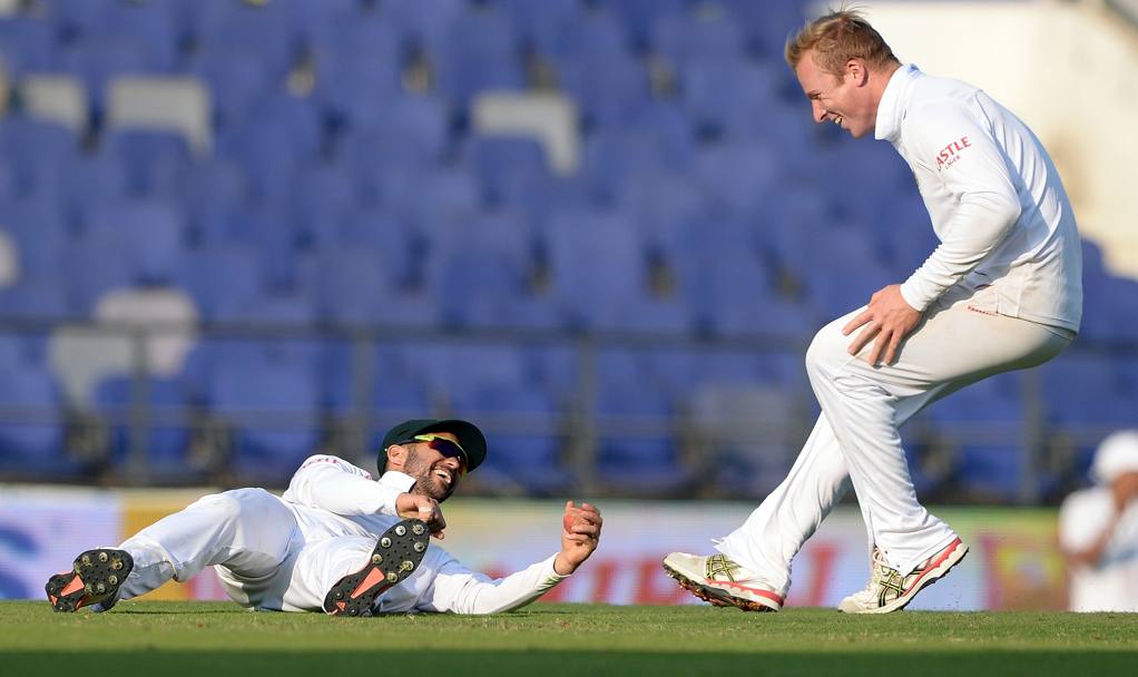 La corsa del sudafricano Simon Harmer verso il compagno di squadra JP Duminy, a terra, durante il test match di cricket contro l&#39;India (Afp)